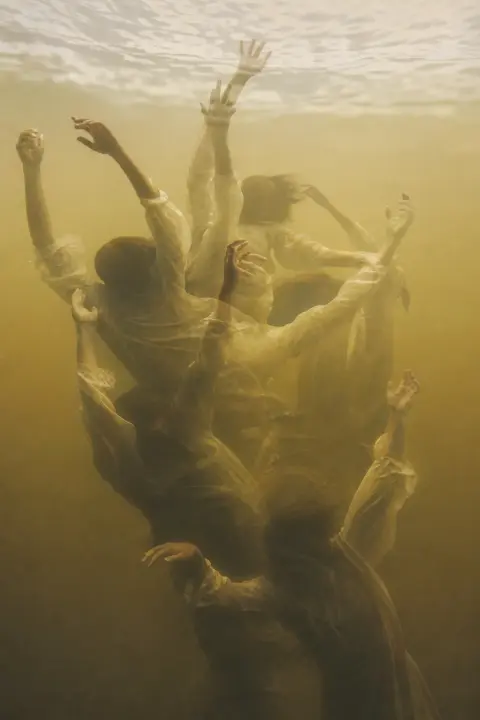 Figure gasping with arms raised while sinking through golden-amber glowing water, overlapping poses capturing drowning struggle and surrender.