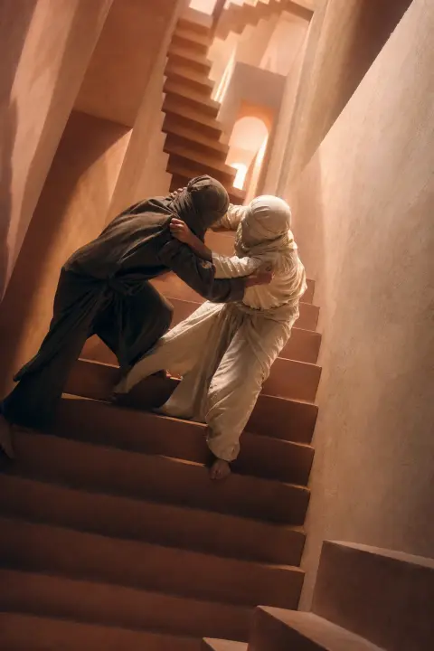 Two figures battle on impossible folding staircase ascending and descending simultaneously through peach corridors